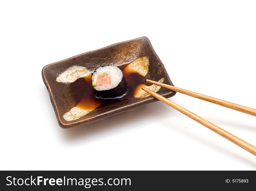 Salmon roll with avocado in soy with chopsticks