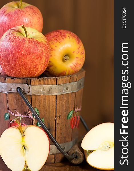 Fresh apples in bucket and on plate against wooden background