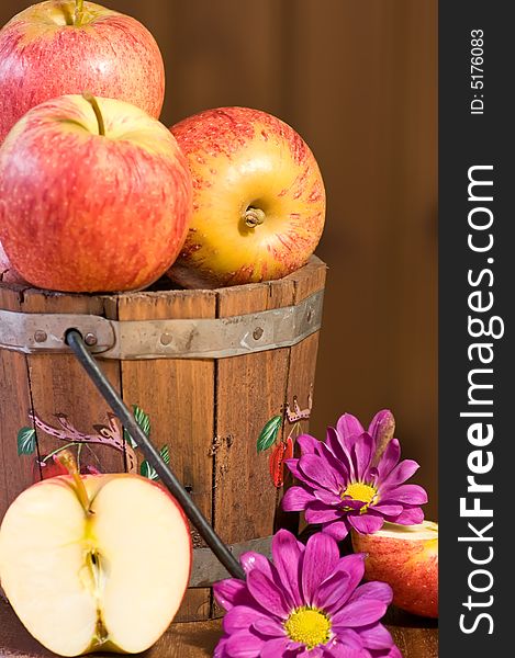 Apples in bucket and flowers against wooden background. Apples in bucket and flowers against wooden background