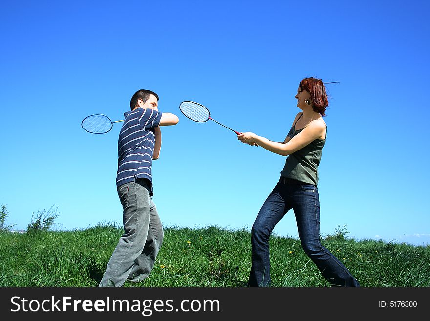 Young couple playing badminton outdoor. Young couple playing badminton outdoor