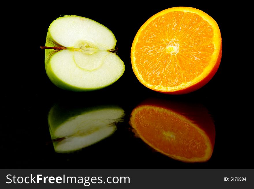 Apple & orange halves isolated against a black background