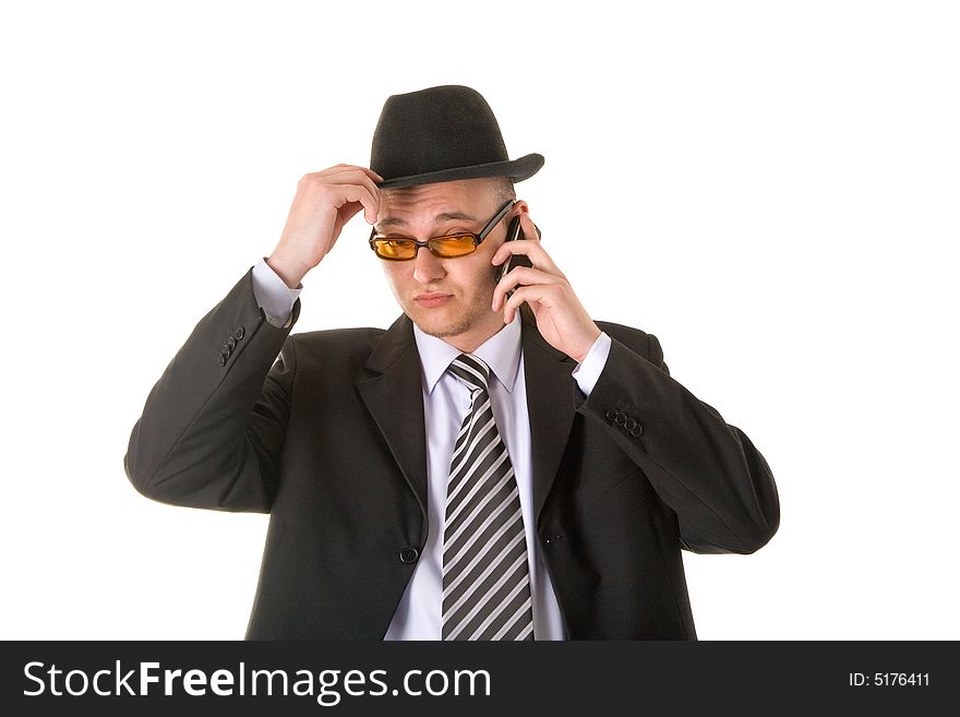 Doubtful businessman in hat and glasses calling on phone