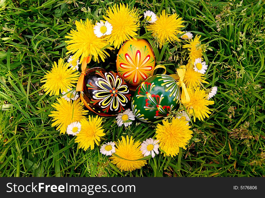 Easter eggs and dandelions chain on grass