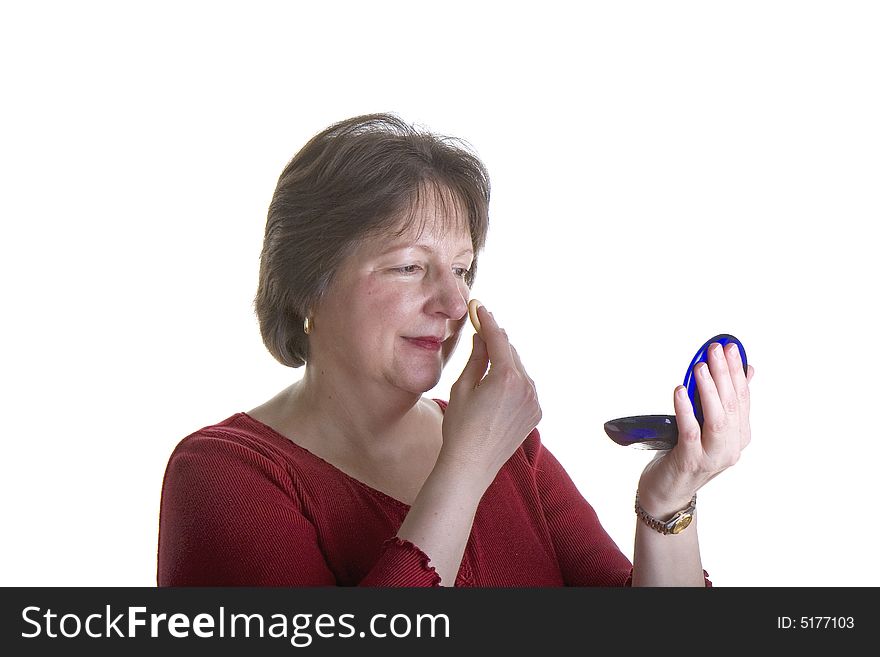 An attractive middle aged woman applying makeup. An attractive middle aged woman applying makeup