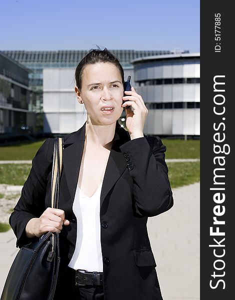 A business woman calling from a mobile phone outdoors. A business woman calling from a mobile phone outdoors