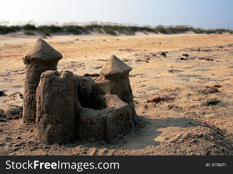 Sand castle on beach with sand dunes in horizon