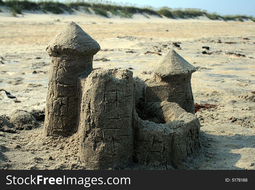 Sand castle on beach with sand dunes in background