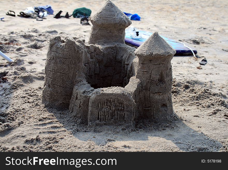 Sand castle on beach with beach supplies in background