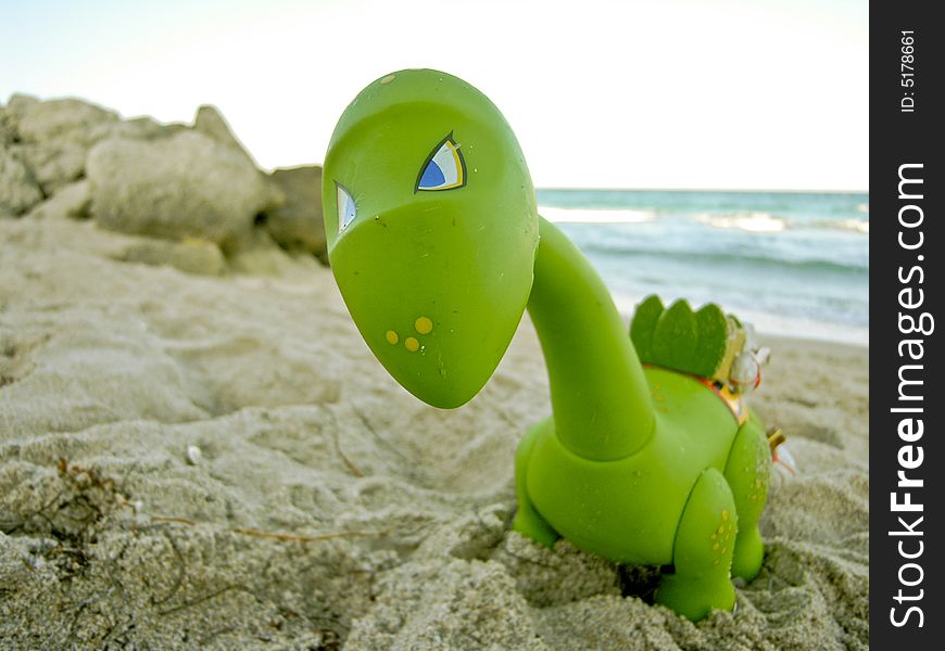 A toy dinosaur on a sandy beach in Florida.