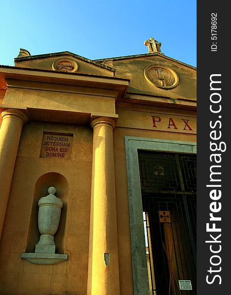 Cemetery entrance front faÃ§ade on blue sky. A sculpted cinerary vase. Christianity, religiorn and death. 
Island of Sicily - Italy. Cemetery entrance front faÃ§ade on blue sky. A sculpted cinerary vase. Christianity, religiorn and death. 
Island of Sicily - Italy