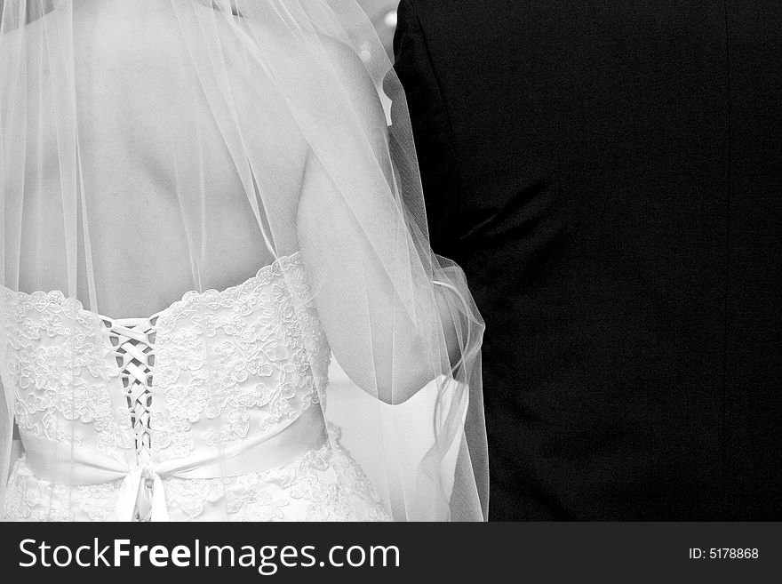 Bride and groom arm in arm, back detail shot, black and white