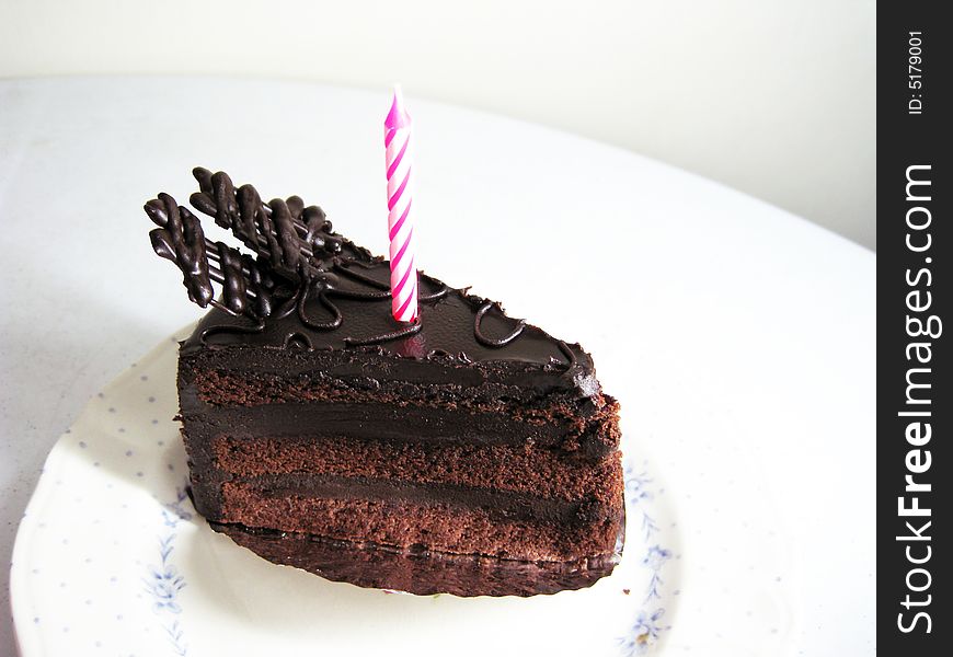 A slide of chocolate cake with candle on top