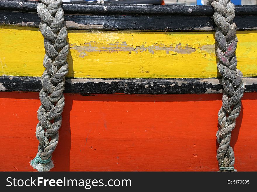 Detail of two ropes, hanging in a boat, yellow and orange