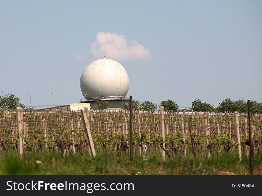 A landscape with an army radar and a vineyard in the front