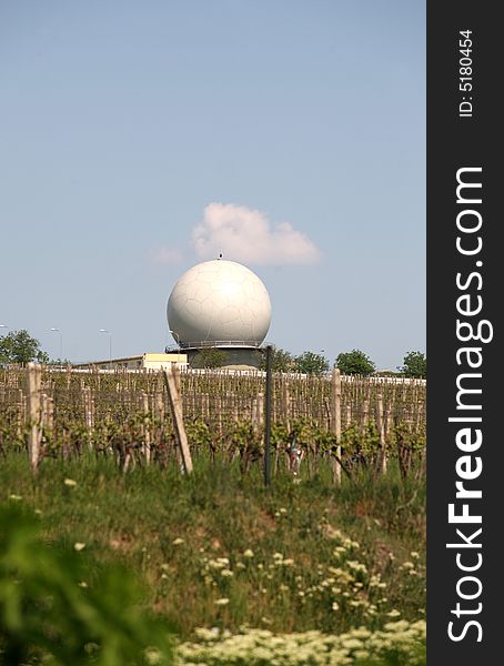 A landscape with an army radar and a vineyard in the front