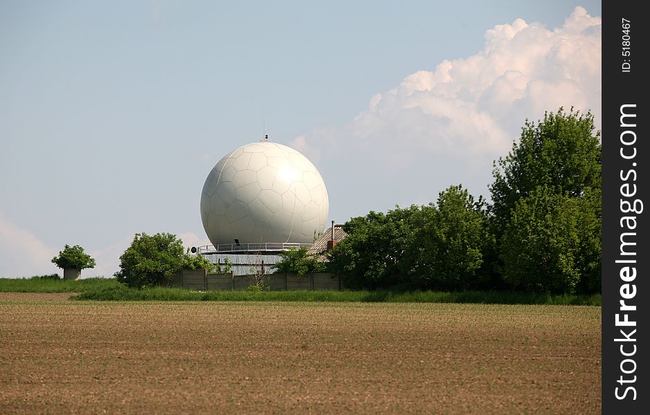 A landscape with an army radar and a field in the front