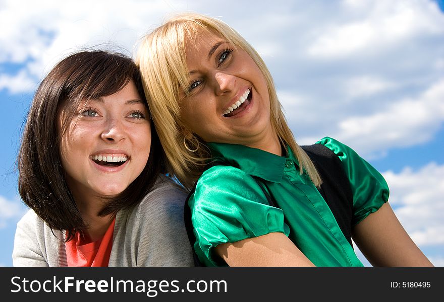 Laughing blonde and brunette portrait on the sky background. Laughing blonde and brunette portrait on the sky background