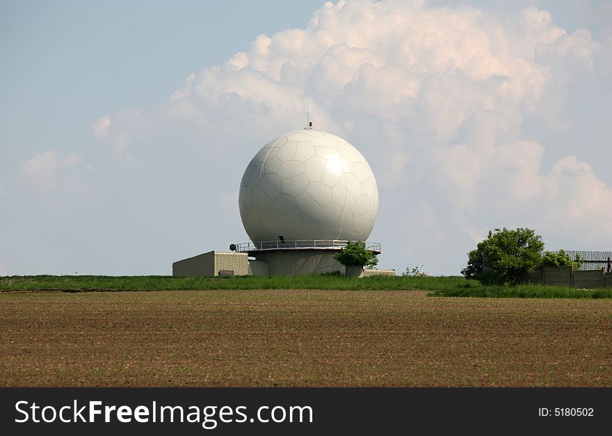 A landscape with an army radar and a field in the front