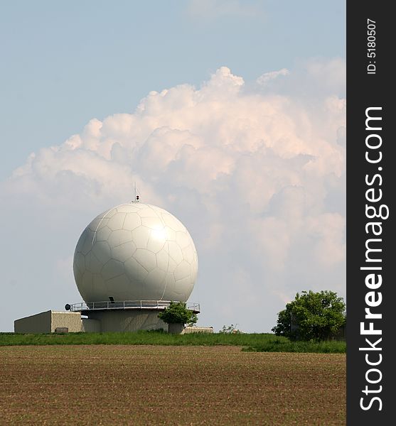 A landscape with an army radar and a field in the front