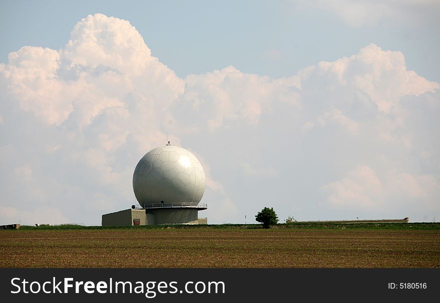 A landscape with an army radar and a field in the front