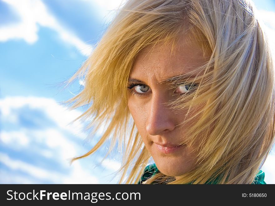 Stylish cute blonde with fly-away hair. Portrait on sky background. Stylish cute blonde with fly-away hair. Portrait on sky background.