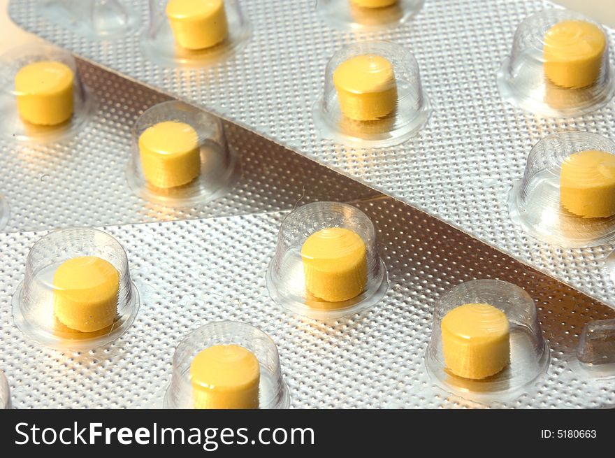 Closeup view of yellow pills in plastic blister from above