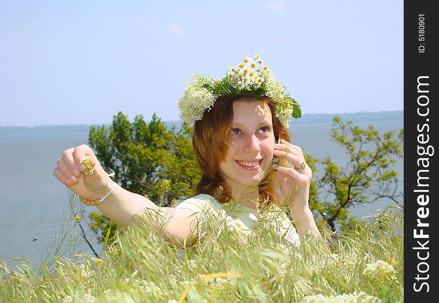 A smiling girl with a chaplet on a head speaks on a mobile telephone. A smiling girl with a chaplet on a head speaks on a mobile telephone.