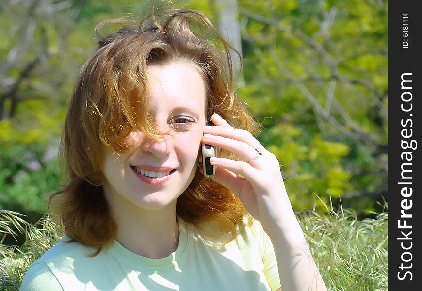 A smiling girl with a chaplet on a head speaks on a mobile telephone. A smiling girl with a chaplet on a head speaks on a mobile telephone.