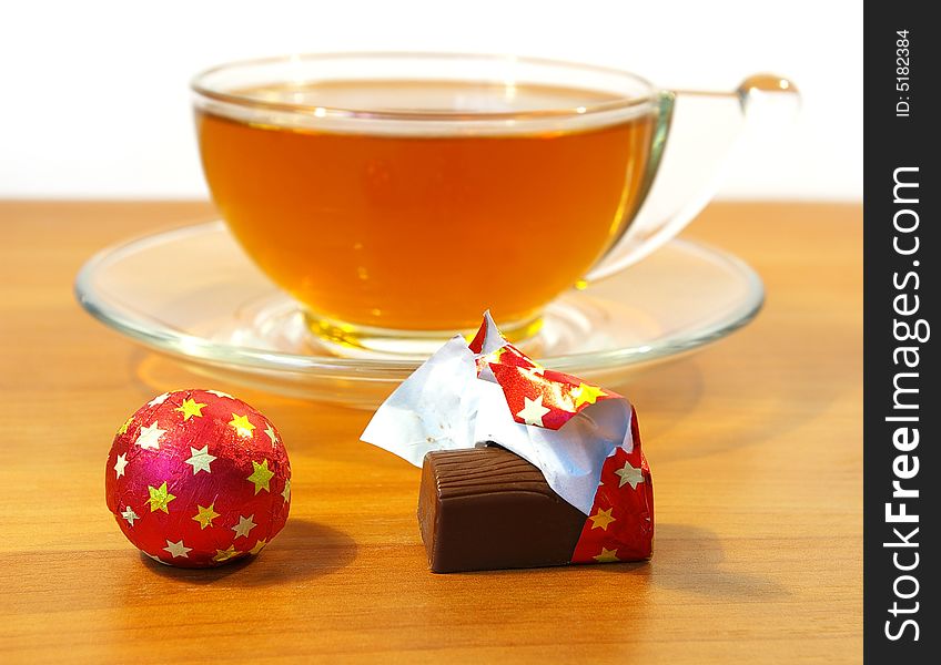 Chocolates in a red wrapper and a cup of tea. Chocolates in a red wrapper and a cup of tea