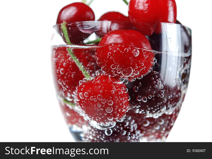 Close up to glass filled with sour cherries in bubbles. Close up to glass filled with sour cherries in bubbles