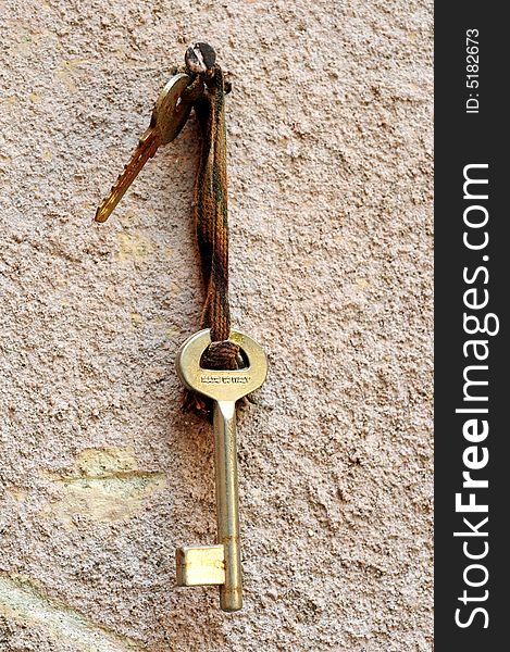 An old key hanging on a textured wall.