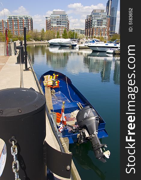 A small aluminum boat with a marine engine at the lakeshore on a sunny day. A small aluminum boat with a marine engine at the lakeshore on a sunny day