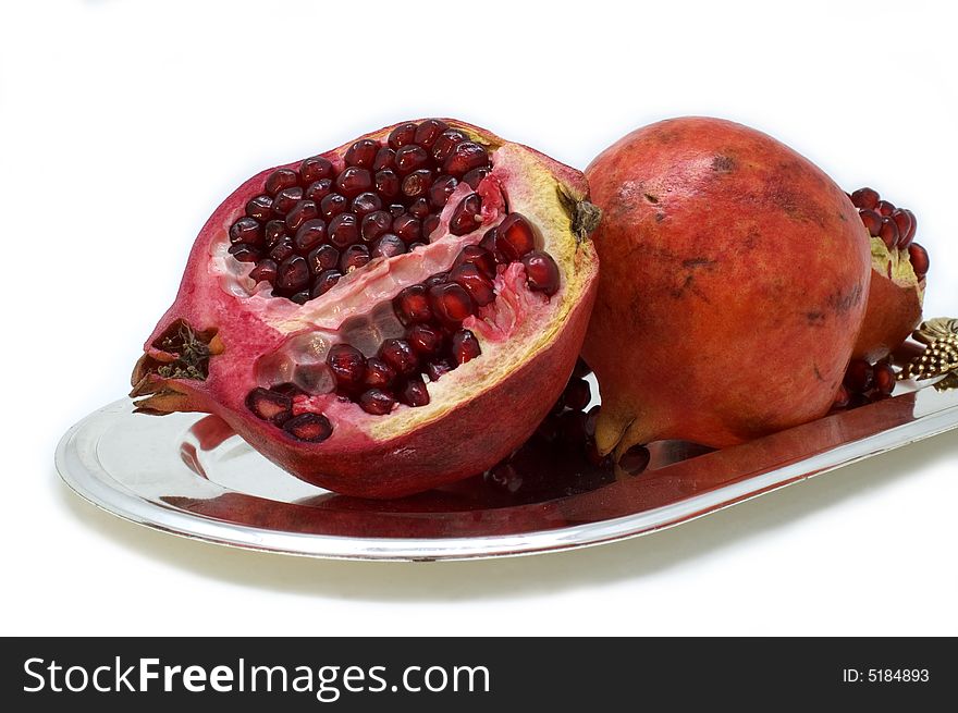 Ripe red pomegranate in a plate on a white background. Ripe red pomegranate in a plate on a white background.