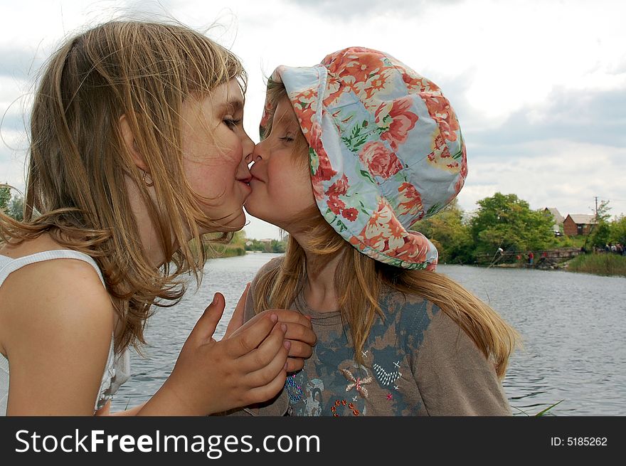 Two lovely kissing girls on the bank of river. Two lovely kissing girls on the bank of river