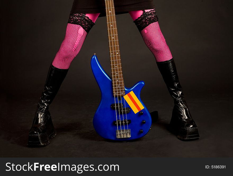 Close-up of woman legs with bass guitar isolated in studio. Close-up of woman legs with bass guitar isolated in studio