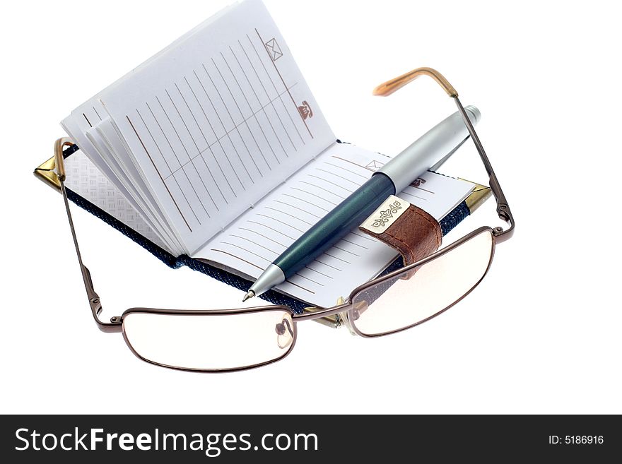 The opened notebook, ball pen and glasses on a white background. The opened notebook, ball pen and glasses on a white background