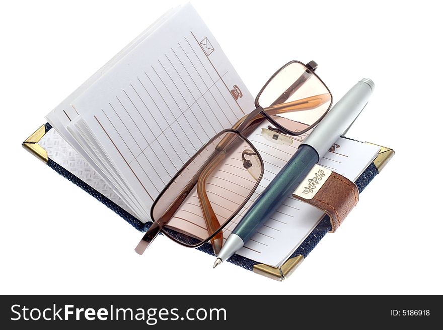 The opened notebook, ball pen and glasses on a white background. The opened notebook, ball pen and glasses on a white background