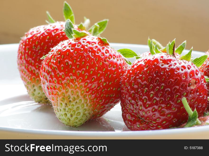 Three delicious strawberries on a white plate