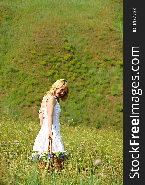 girl walk away with basket on a meadow. Girl half turn and look at camera. girl walk away with basket on a meadow. Girl half turn and look at camera.