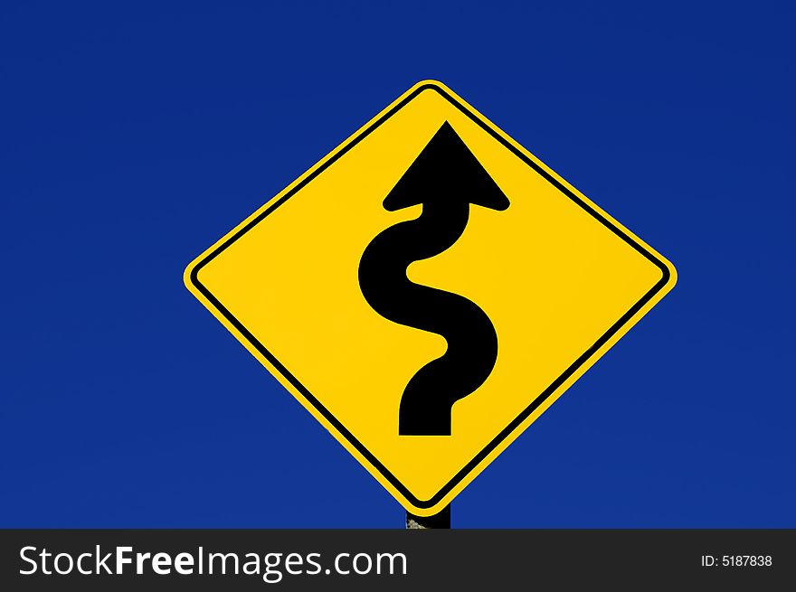 Yellow street sign with curves against blue sky. Yellow street sign with curves against blue sky