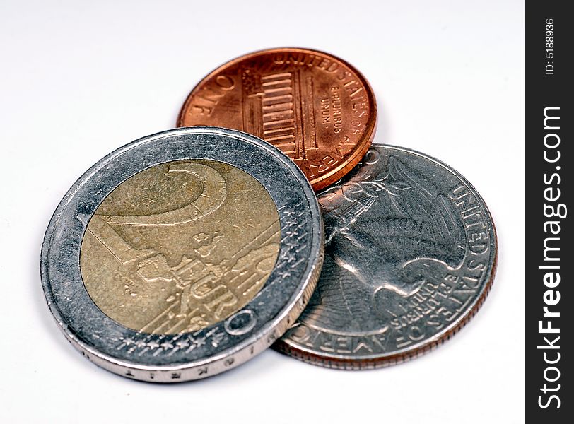 A close up with euro coins against dollars over a white background. A close up with euro coins against dollars over a white background