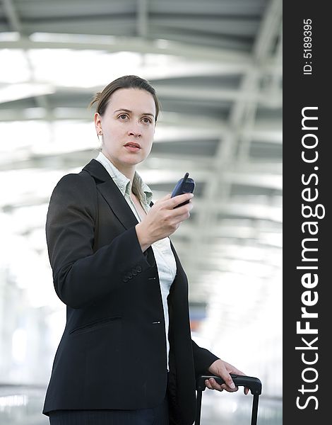 A business woman in an airport setting with a cellular phone. A business woman in an airport setting with a cellular phone