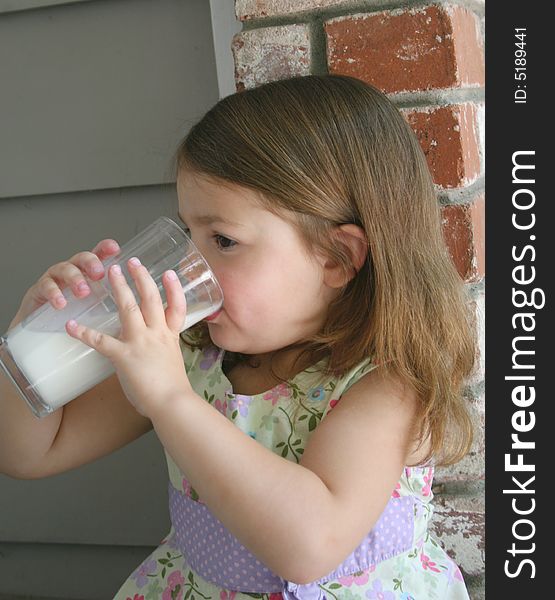 A healthy little girl drinking a fresh glass of cold milk. A healthy little girl drinking a fresh glass of cold milk