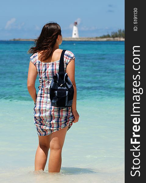 The girl standing on Nassau beach with a lighthouse in a background (The Bahamas).