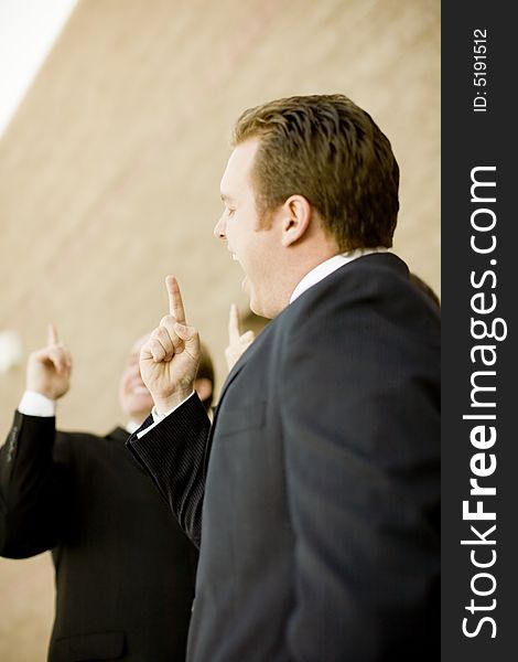 Businesspeople standing together with hands pointing upward and smiling. Businesspeople standing together with hands pointing upward and smiling