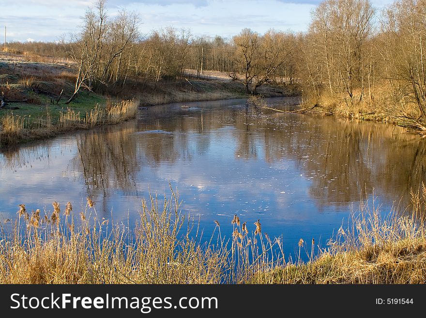 Non-urban lanscape with leafless trees, grass and river. Non-urban lanscape with leafless trees, grass and river