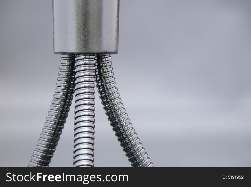 A Bendy metal camera tripod isolated against a blue grey background to enhance the metallic finish. A Bendy metal camera tripod isolated against a blue grey background to enhance the metallic finish.