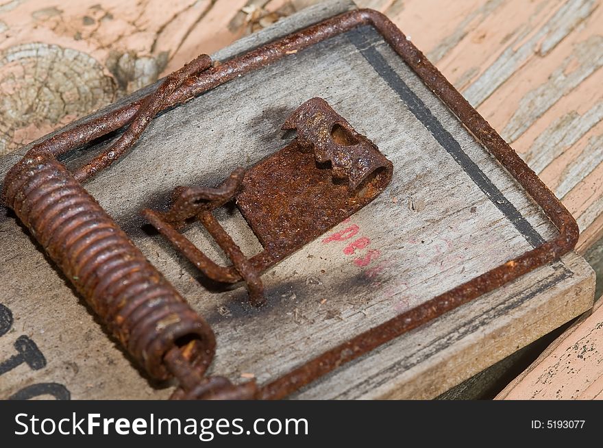 A rusted old mousetrap on weathered wood