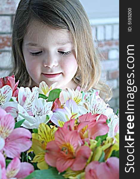 A little girl looks thoughtfully into a bunch of fresh cut flowers. A little girl looks thoughtfully into a bunch of fresh cut flowers
