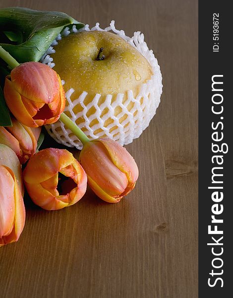 Asian (Nashi) Pear on wood table with orange tulips. Natural light.